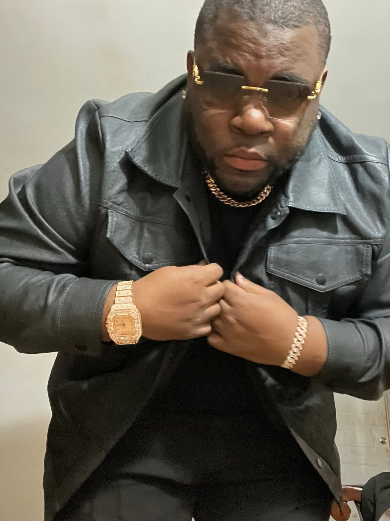 Greg Lauture in a black leather jacket, glasses and gold jewelry
